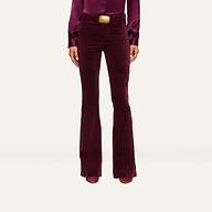 A person wearing a long-sleeved, burgundy blouse tucked into matching high-rise Marty Velvet Pants with a wide belt, standing against a plain background.