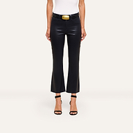 A person wears the Kendra Coated Cropped Flare Jean, a white sleeveless top, a black belt with a large gold buckle, and black heeled sandals, standing against a plain light background.