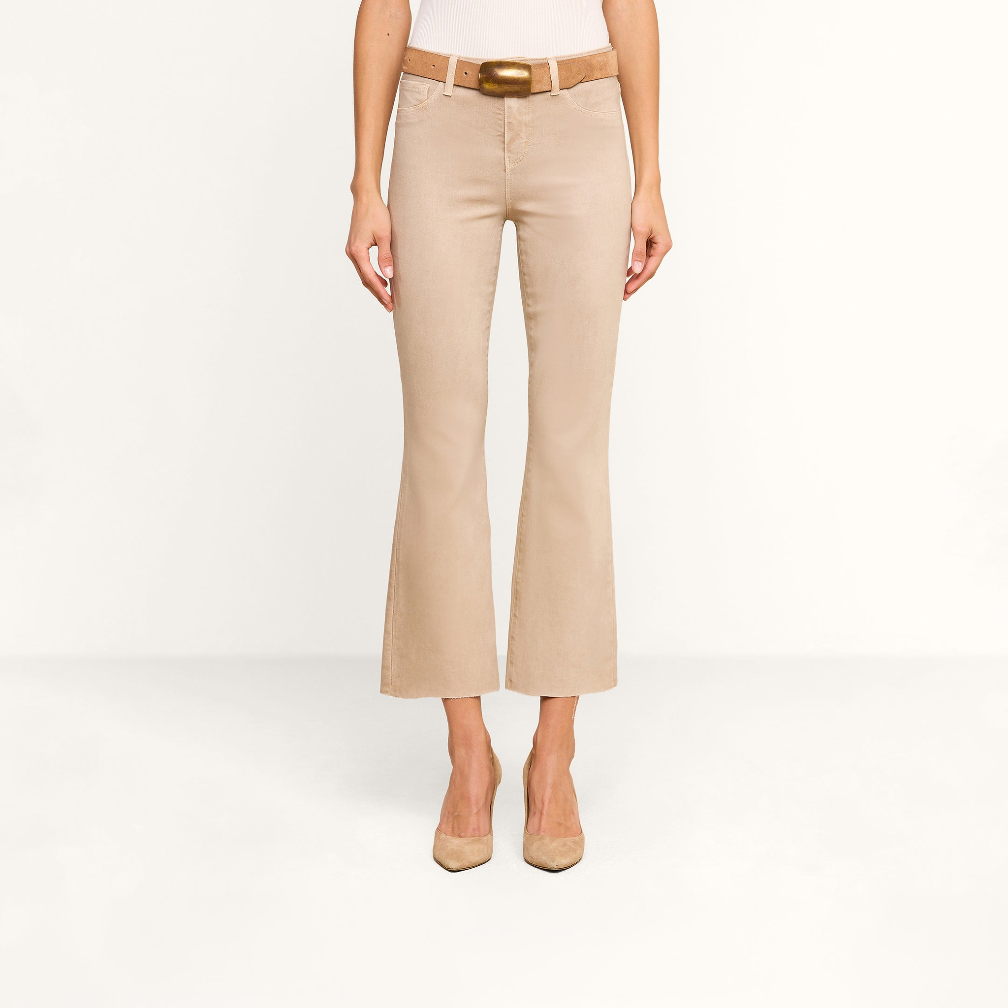 A person is shown from the waist down, facing forward against a plain white background, wearing the Kendra Coated Cropped Flare Jean with a matching belt and beige heels.