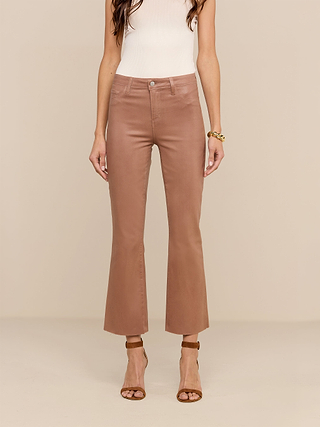 A woman wears the Petite Kendra Coated Jean, styled with a white sleeveless top, brown heeled sandals, and a gold bracelet, standing against a beige background.
