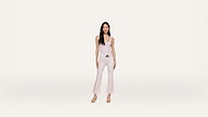 A woman stands facing forward, wearing a light pink sleeveless top, matching flared pants, and beige heels against a plain white background.