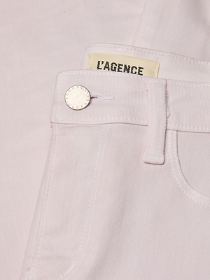 Close-up of a light pink denim pocket with a button and 'L'Agence' label.