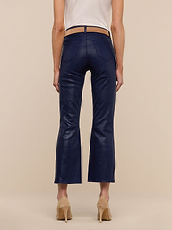 A person wearing the Kendra Coated Cropped Flare Jean in dark blue, paired with a beige top and tan high-heeled shoes, is standing facing away from the camera against a plain white background.
