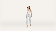 A woman wearing a white tank top, light blue flared jeans, and heeled sandals stands against a plain white background.