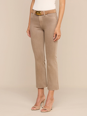 Une personne porte le jean évasé court enduit « Kendra » de couleur beige, avec une ceinture marron et des sandales à talons beiges, debout devant un fond clair uni. Seule la partie inférieure de son corps est visible.