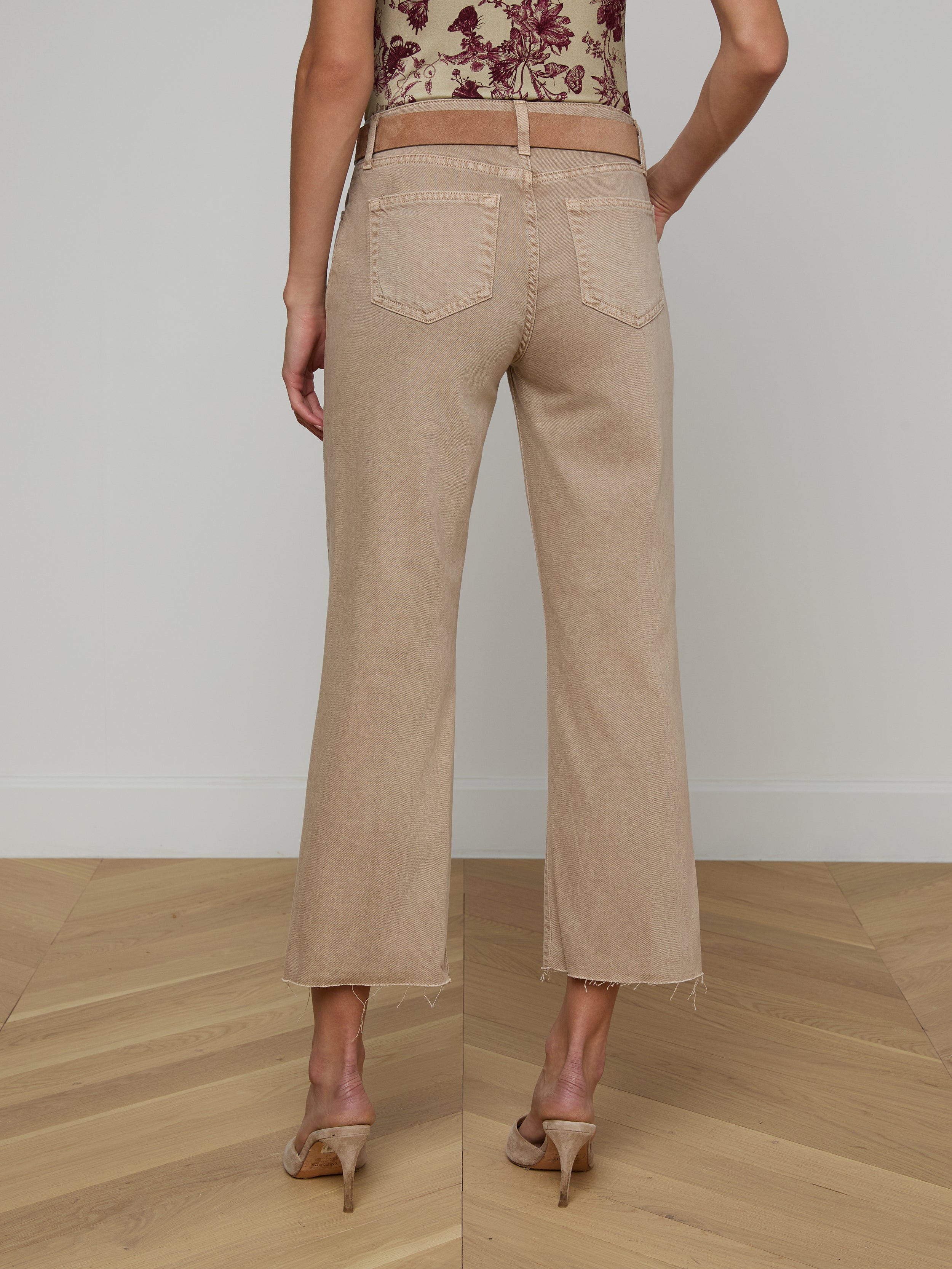 A person wearing Wanda Cropped Wide-Leg Jeans in a neutral tan color and heeled sandals, shown from the back, standing against a plain white background.