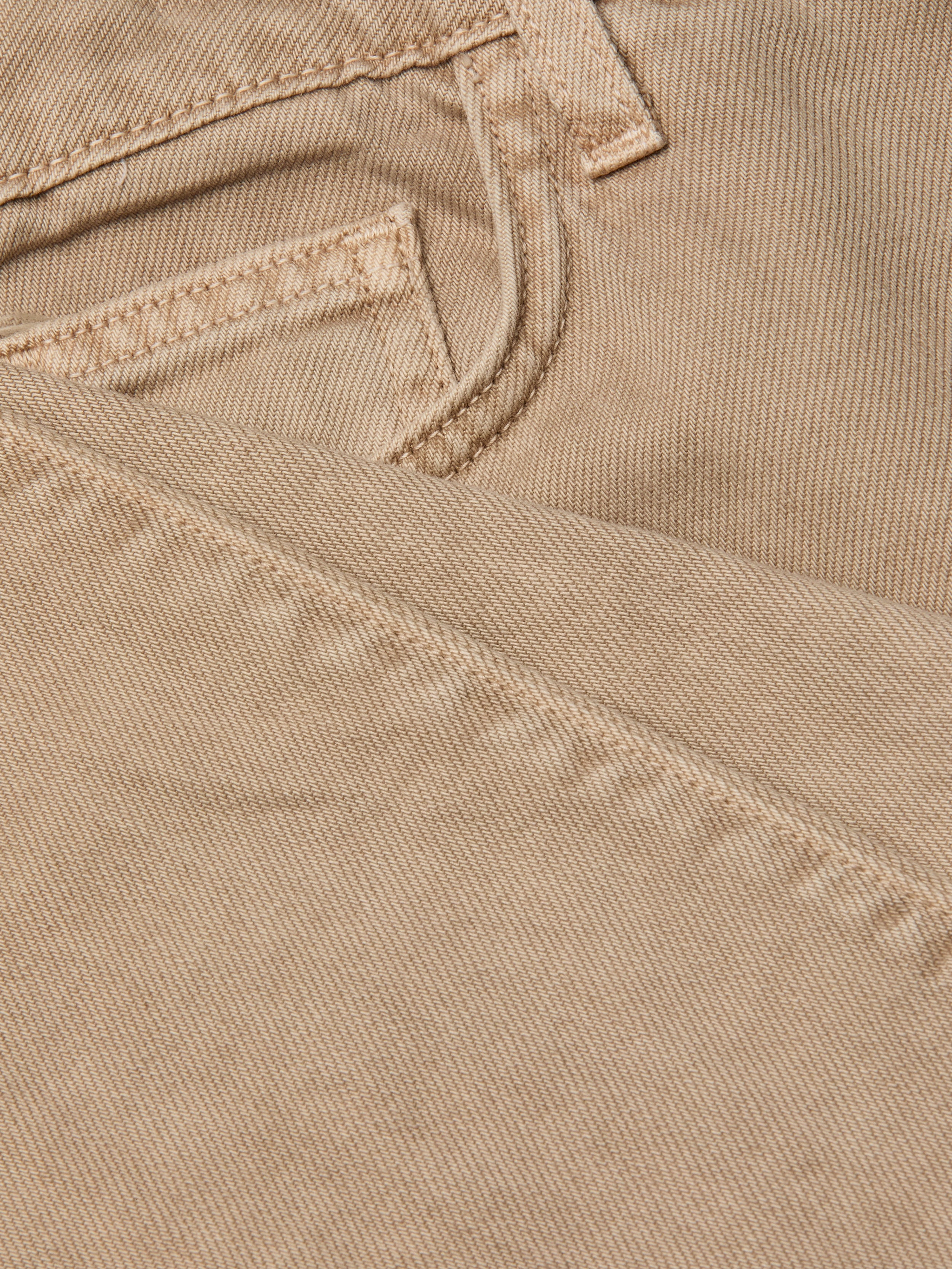 Close-up of the neutral tan denim fabric of the Wanda Cropped Wide-Leg Jean, highlighting a jeans pocket and detailed stitching, with one section of the material folded over the other.