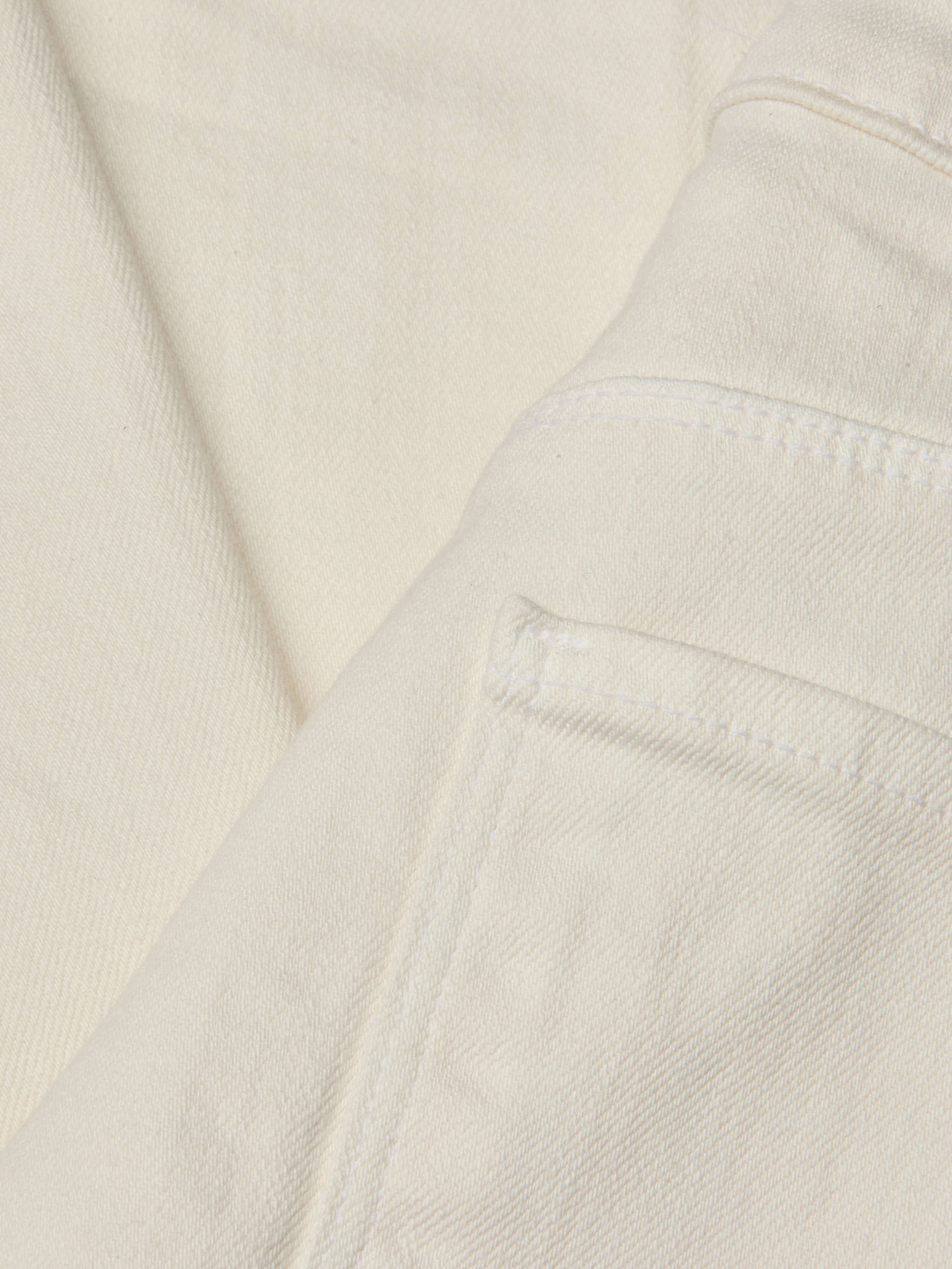 Close-up of the Wanda Cropped Wide-Leg Jean in a lightweight ecru-wash denim, highlighting stitched seams, a folded edge, and part of the pocket. The image showcases the fabric’s texture and weave in detail.