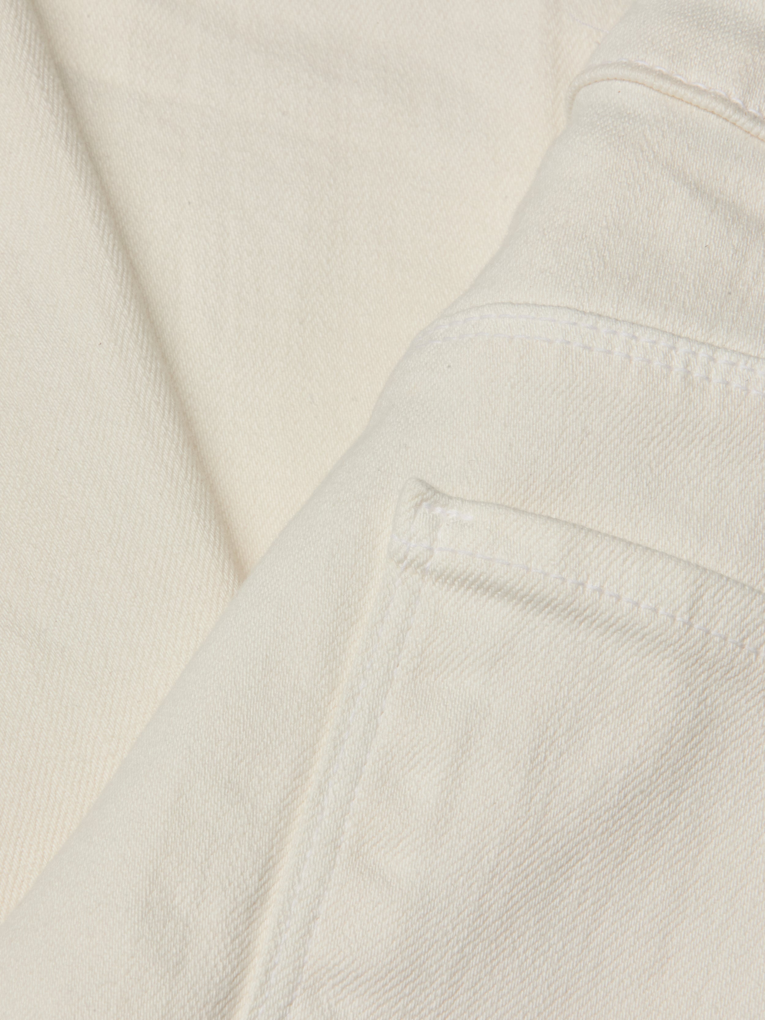 Close-up of the Wanda Cropped Wide-Leg Jean in a lightweight ecru-wash denim, highlighting stitched seams, a folded edge, and part of the pocket. The image showcases the fabric’s texture and weave in detail.