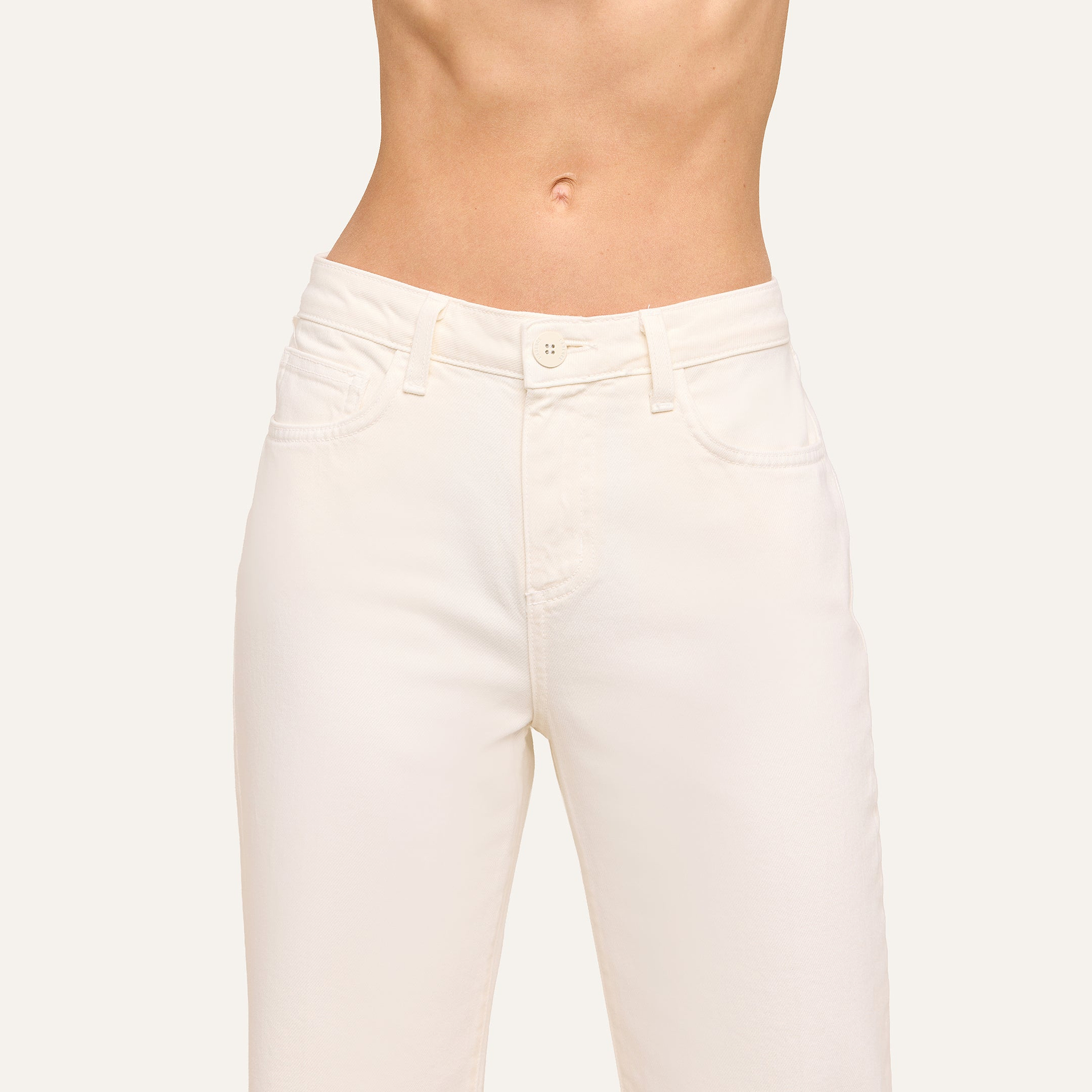 A person wears the Wanda Cropped Wide-Leg Jean in off-white, high-waisted style, showing a bare midriff. The image is cropped from chest to thighs to highlight the jean’s fit and details.