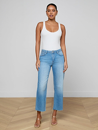 A woman stands against a plain background, wearing a white tank top, tan heeled sandals, and the Wanda Cropped Wide-Leg Jean in light blue all-cotton denim.