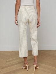 A woman stands facing away, wearing the Wanda Cropped Wide-Leg Pant in a cream nautical stripe and beige high heels against a plain background.