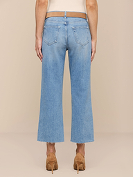 Eine Person ist von hinten in einer hellblauen Wanda Cropped Wide-Leg Jeans mit ausgefransten Säumen, hellbraunen Stöckelschuhen und einem ärmellosen beigen Oberteil vor einem neutralen Hintergrund abgebildet.