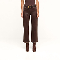 A person wearing the Wanda Coated Cropped Wide-Leg Jean with a black belt and brown suede boots, standing against a beige background.