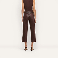 A person stands facing away against a plain background, wearing the Wanda Coated Cropped Wide-Leg Jean in dark java brown, paired with a sleeveless top and heeled sandals.