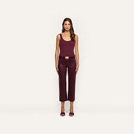 A woman stands facing forward, wearing a sleeveless burgundy top, the Wanda Coated Cropped Wide-Leg Jean with a belt, and burgundy heels against a plain light background.