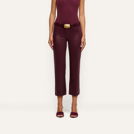 A woman is wearing the Wanda Coated Cropped Wide-Leg Jean, paired with a sleeveless burgundy top and open-toed shoes, standing against a plain light background. Her head is not visible in the image.