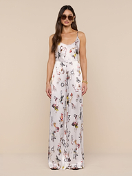A woman in sunglasses wears the Kimia Satin Pant—a white, high-rise, straight-leg style—paired with a sleeveless floral top, standing against a plain white background and facing forward with her hands by her sides.