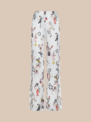 The Kimia Satin Pant is a high-rise, wide-leg white pant with a whimsical cartoon print of playful characters and objects on a beige background.