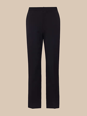 The Rebel Trouser is a black, straight-leg womens pant with a fitted high-rise waist and tailored design, made from Italian stretch suiting fabric and shown against a beige background.