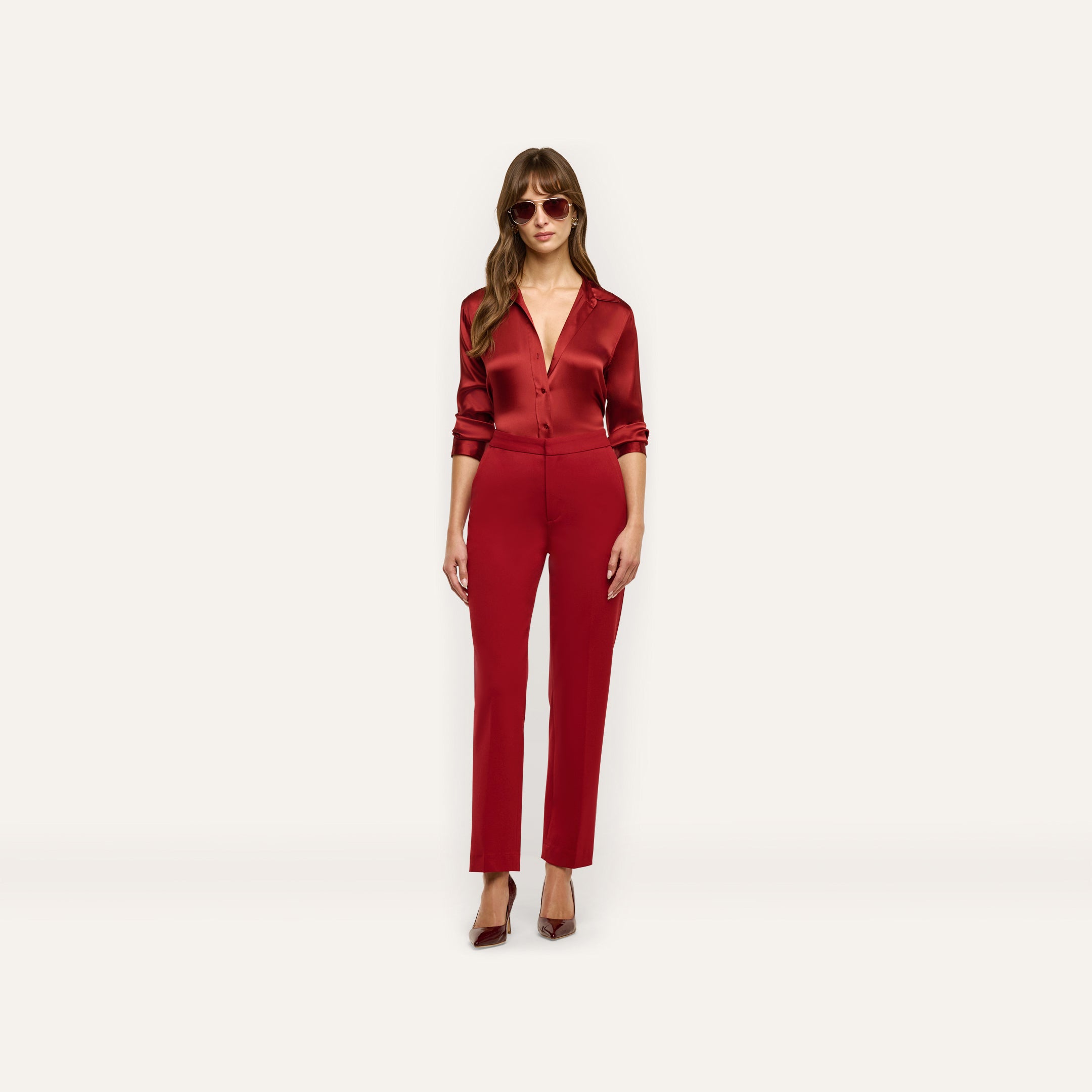 A person wearing a long-sleeved red button-down shirt tucked into slim-straight Rebel Trouser trousers and red pointed-toe heels, creating a tailored statement look.