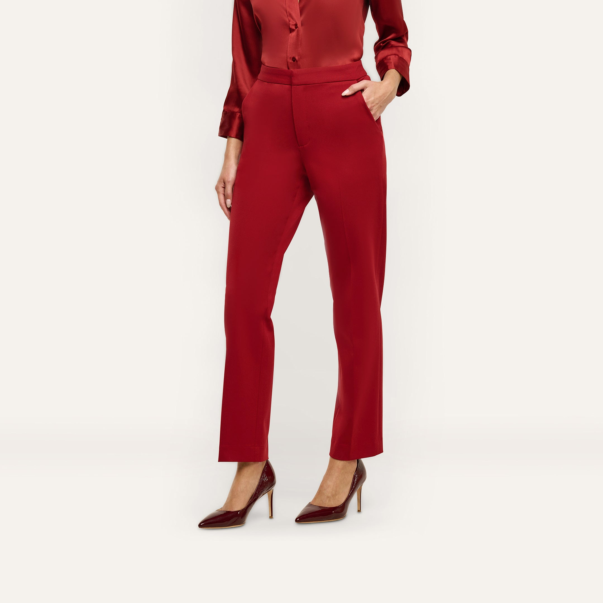 Rebel Trouser: mid-rise slim-straight red trousers in stretch twill suiting with side pockets, worn with a matching long-sleeved silk blouse and dark pointed-toe heels.