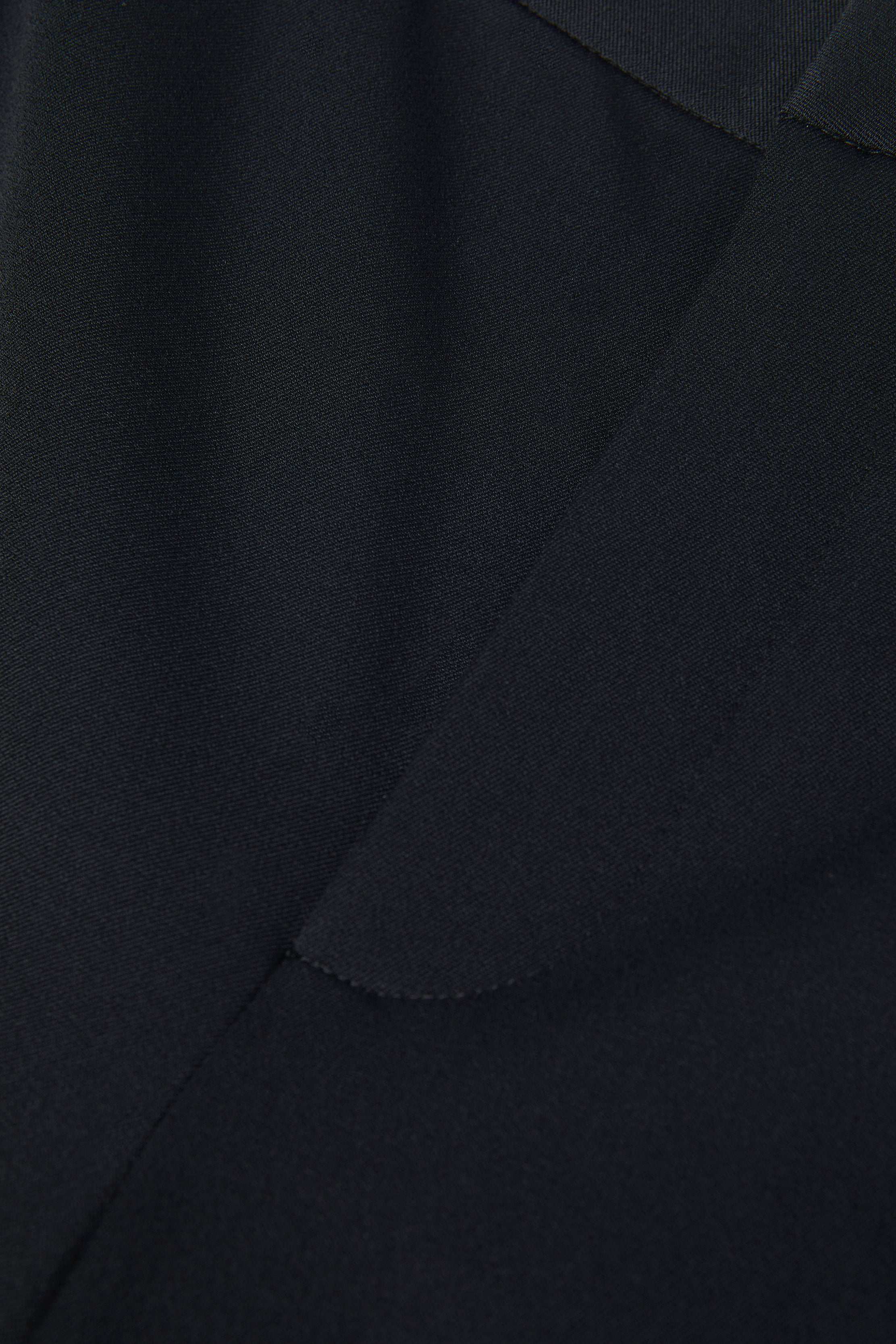 Close-up of the Rebel Trouser in dark navy blue, crafted from Italian stretch suiting, highlighting the fabric texture and edge detailing.