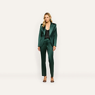 A woman wearing a dark green satin blazer and Rebel Satin Trouser over a black camisole, finished with black heeled sandals for a tailored statement.