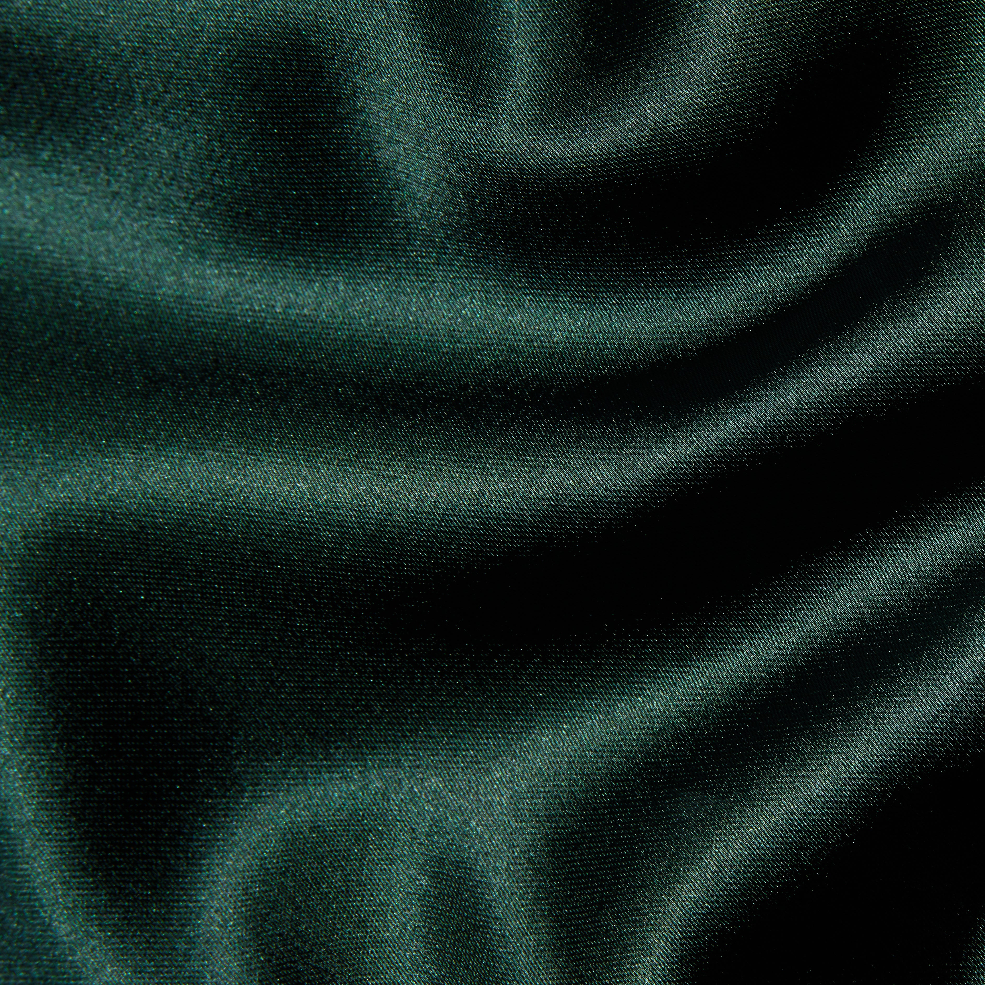 Close-up of the deep green Rebel Satin Trouser, featuring a smooth, glossy texture and soft folds that highlight a tailored statement.