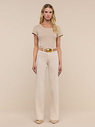 A woman stands facing forward, wearing a beige short-sleeve top, beige shoes, and the Clayton Wide-Leg Jean in a matching high-rise, tall wide-leg style with a belt, against a plain white background.