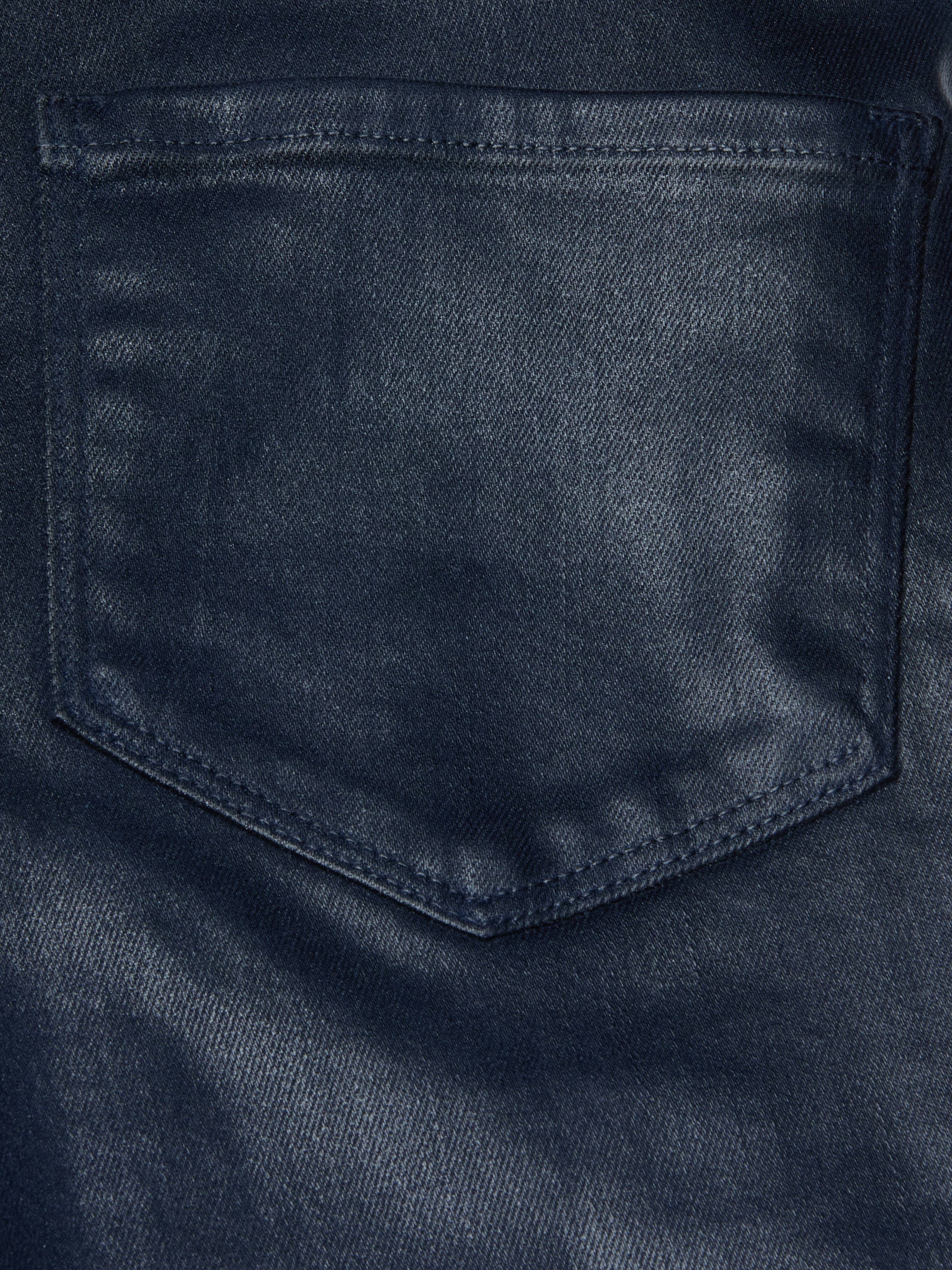 Close-up of the Clayton Coated Wide-Leg Jean by L'AGENCE in dark blue, highlighting the back pocket with visible stitching. The texture and weave of the high-quality coated denim are clearly shown.