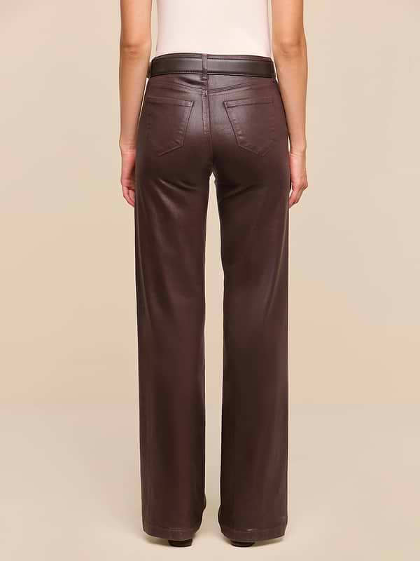 A person stands facing away, wearing the Clayton Coated Wide-Leg Jean in brown paired with a sleeveless beige top against a plain white background.