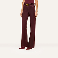 A person models the Clayton Coated Wide-Leg Jean, featuring a high waist, wide-leg silhouette, contoured waistband, and matching belt in burgundy leather. They pair the jeans with pointed burgundy heeled shoes. The top of their head is not visible.