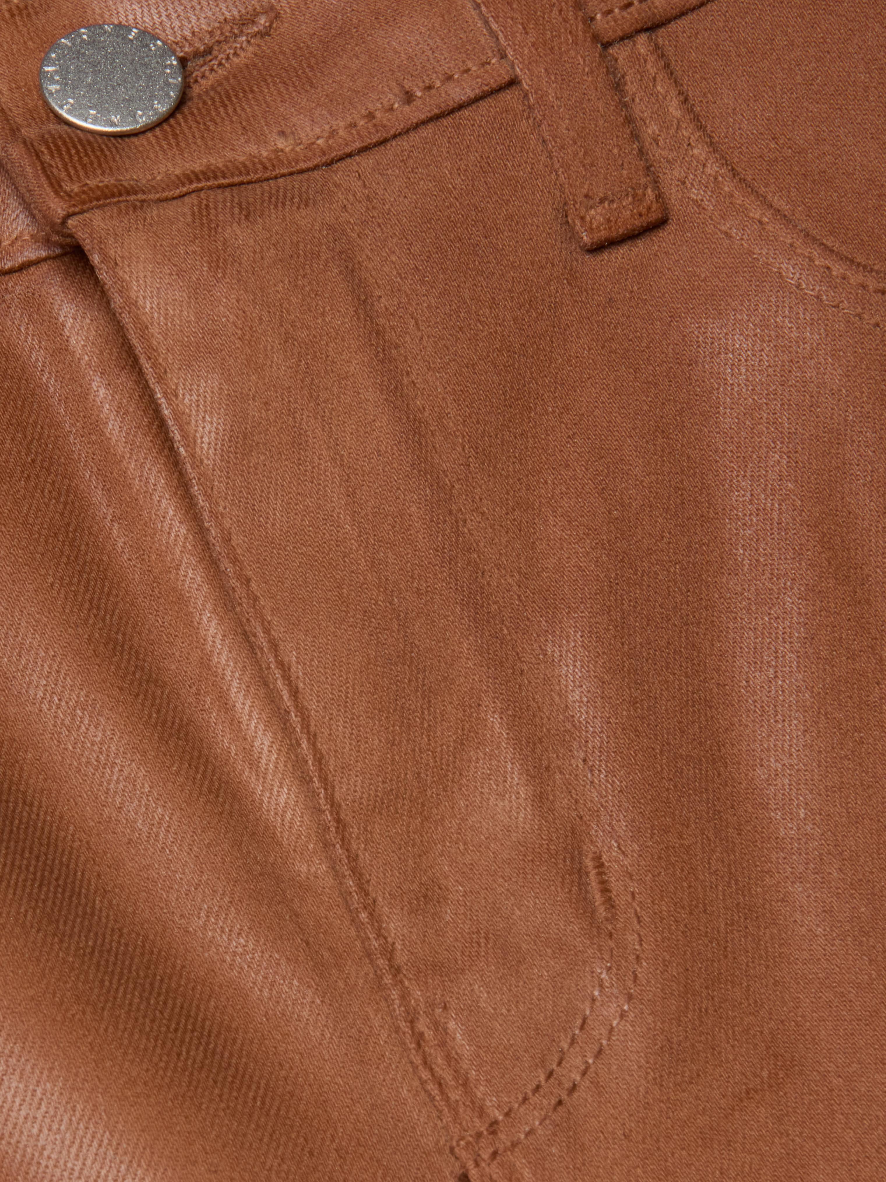Close-up of the front pocket and contoured waistband on the L'AGENCE Clayton Coated Wide-Leg Jean, featuring brown coated denim, a metallic button, belt loop, and detailed stitching.