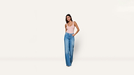 A woman in a pale pink tank top and blue wide-leg jeans, standing with her hand in her pocket.