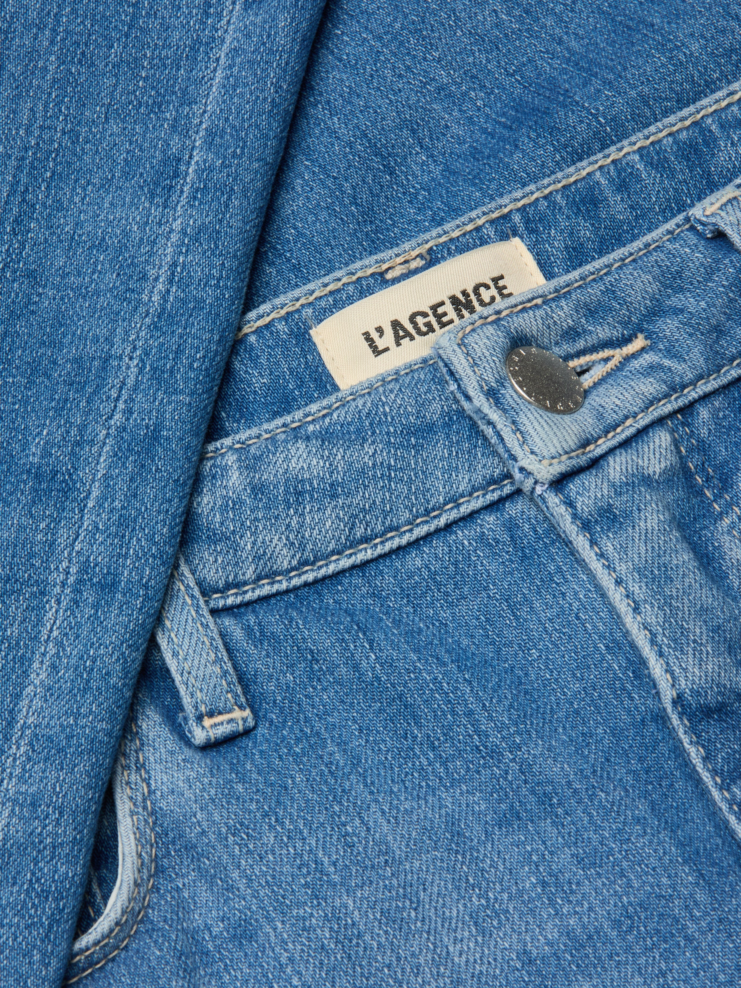 Close-up of the Clayton Wide-Leg Jean in blue denim, featuring a silver button, visible LAGENCE brand label, detailed stitching, and high rise stretch denim fabric.
