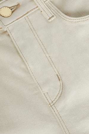 Close-up of the front pocket and waistband of the Beau Wide-Leg Jean in light beige denim, featuring detailed stitching and a metal button with a textured edge.