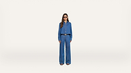 A person wearing sunglasses, a blue button-up shirt, and matching wide-leg blue pants stands facing forward against a plain white background.