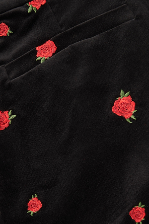 Close-up of the Livvy Velvet Trouser, featuring black velvet fabric with red rose embroidery and green leaves, highlighting the pocket seam on these straight-leg pants.