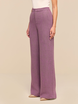 A person wearing the Livvy Straight-Leg Trouser in purple herringbone, styled with beige pointed-toe heels and standing against a plain beige background.