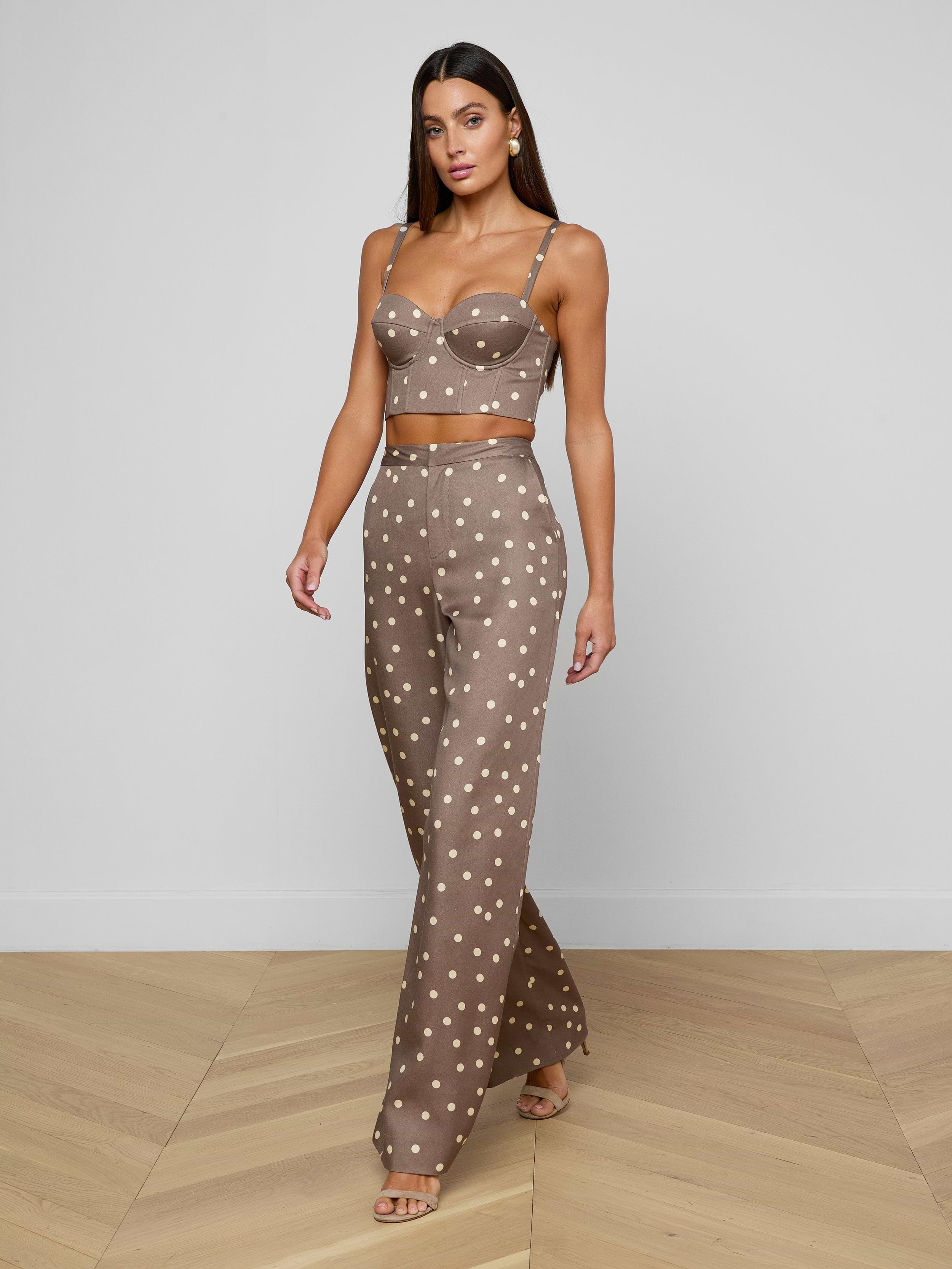 A woman is wearing the Livvy Straight-Leg Trouser as part of a brown, polka dot two-piece outfit, which includes a crop top with thin straps and high-rise, straight-leg trousers. She stands against a plain white background.