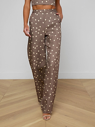 Wearing the Livvy Straight-Leg Trouser featuring a brown polka dot print, a model walks forward against a plain background, styled with a matching crop top and open-toe heels.