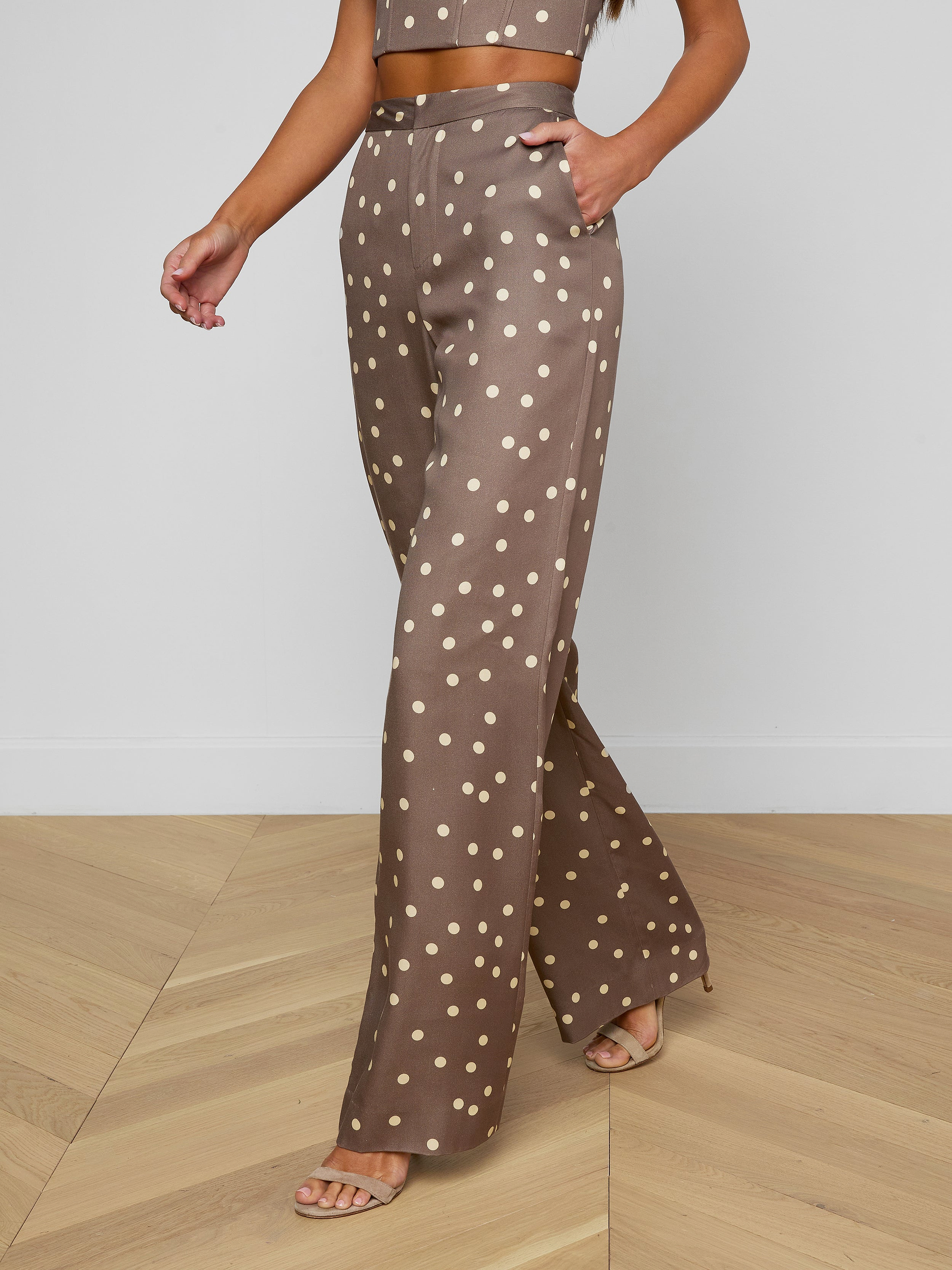 A person wearing the Livvy Straight-Leg Trouser in brown with a white polka dot print, paired with a matching crop top and beige heels, walking against a plain background.