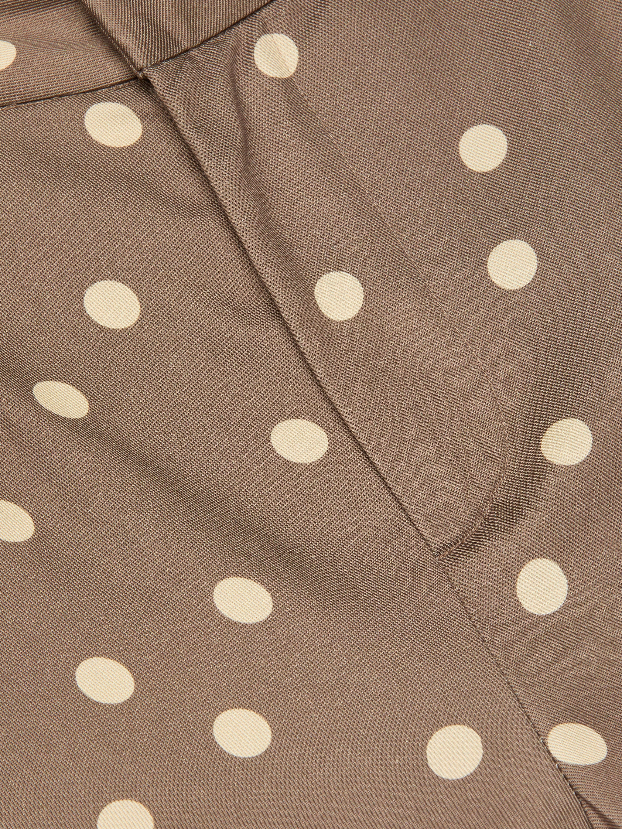 Close-up of brown fabric with a cream polka dot print and a vertical seam through the center, reminiscent of the Livvy Straight-Leg Trouser.