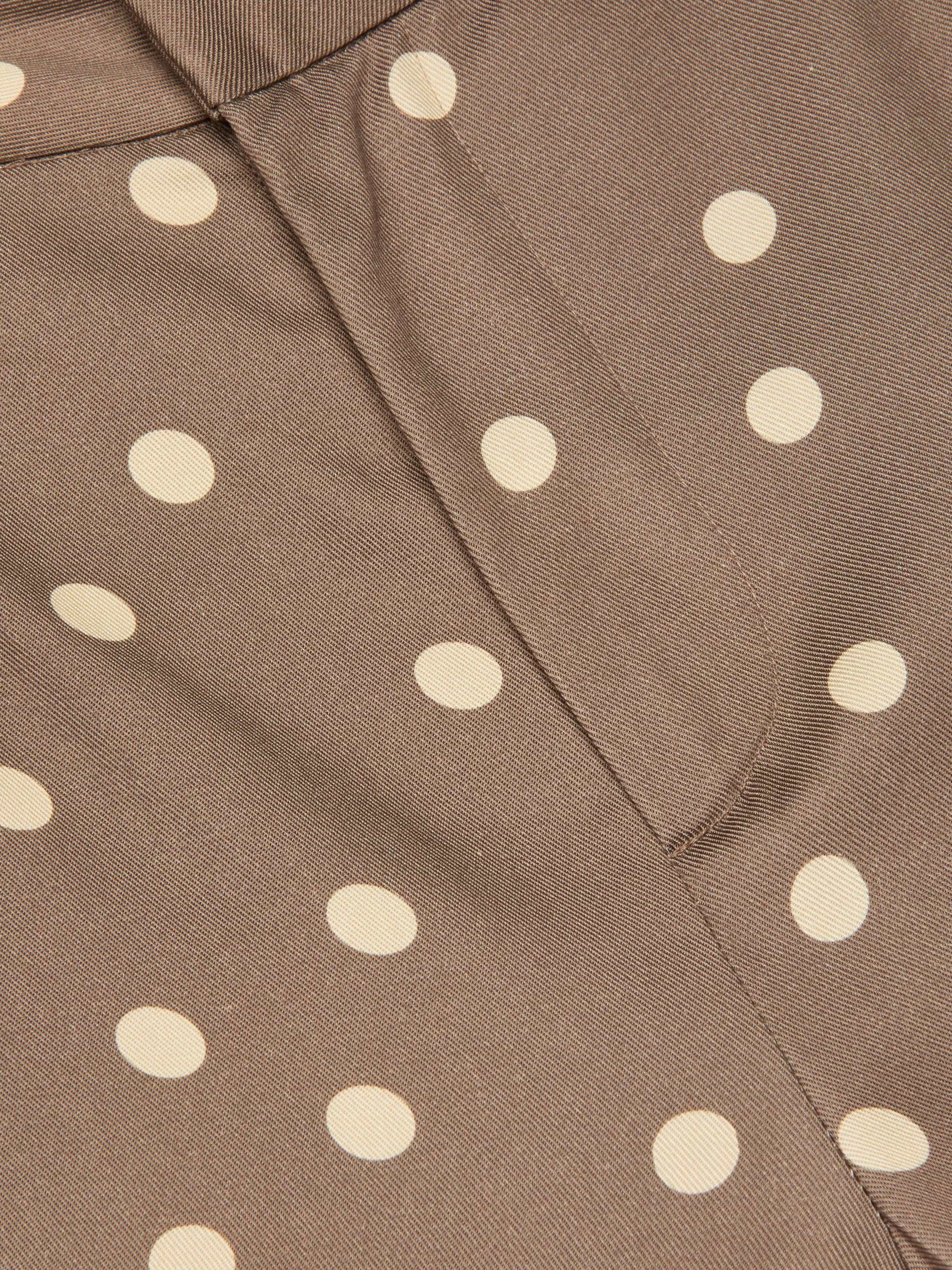 Close-up of brown fabric with a cream polka dot print and a vertical seam through the center, reminiscent of the Livvy Straight-Leg Trouser.