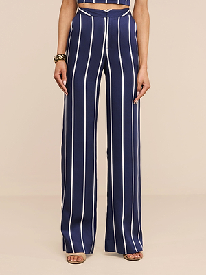 Une personne présente le Livvy Trouser - un pantalon rayé marine à taille haute et à jambe large en tencel léger - associé à des talons ouverts de couleur bronze et à un crop top rayé assorti. Seul le corps de la personne est visible à partir des épaules.