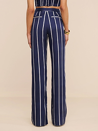 Una persona indossa i pantaloni Livvy - pantaloni a vita alta e a gamba larga in tencel leggero, con strisce verticali bianche e tasche posteriori bordate di bianco. Mostrati da dietro, abbinati a un top senza maniche.