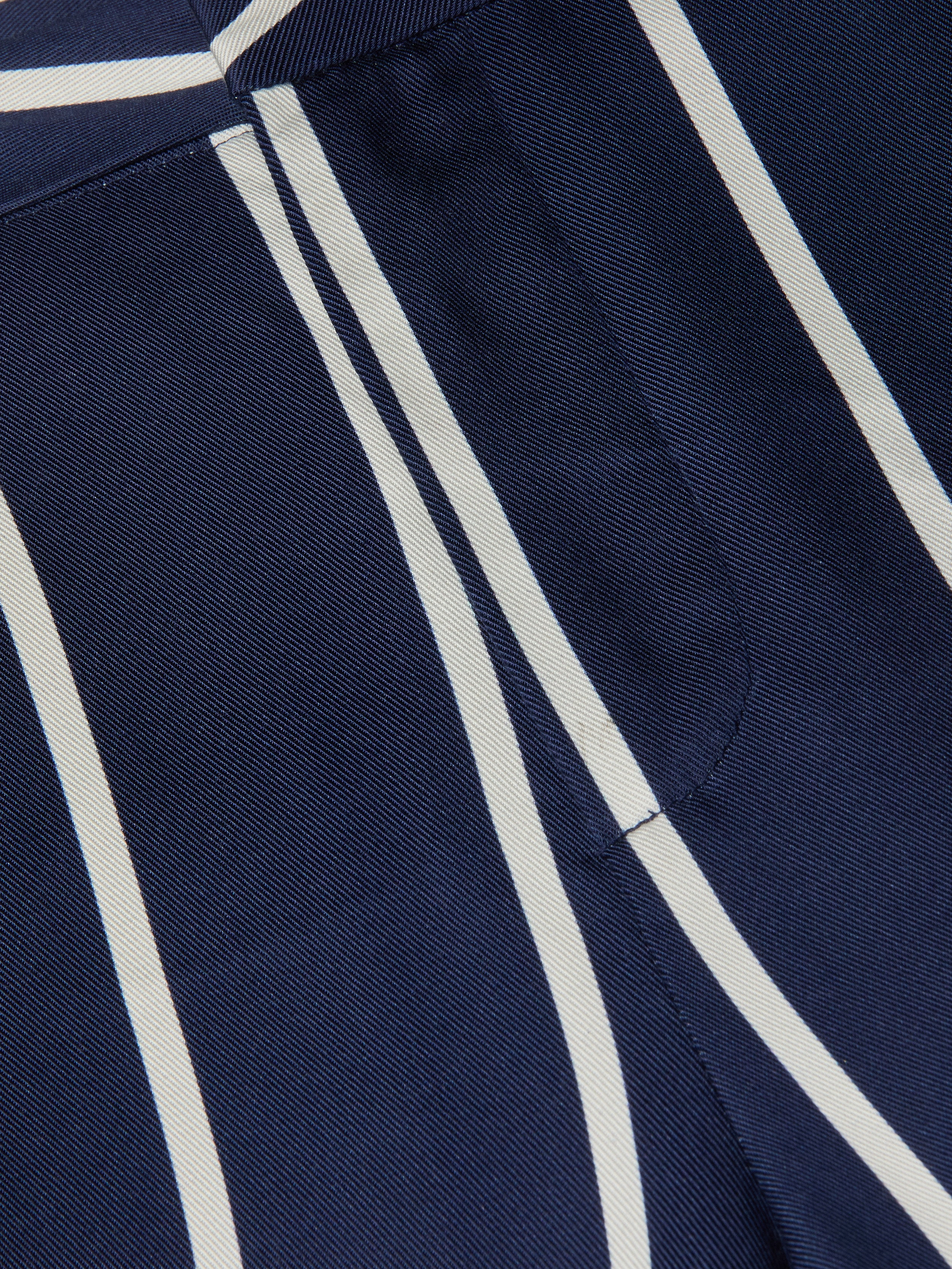 Primo piano del pantalone Livvy, che mostra il suo leggero tessuto Tencel, la tonalità navy con strisce verticali bianche, il taglio a gamba dritta e la tasca laterale ben cucita che mette in risalto sia la texture che il motivo.