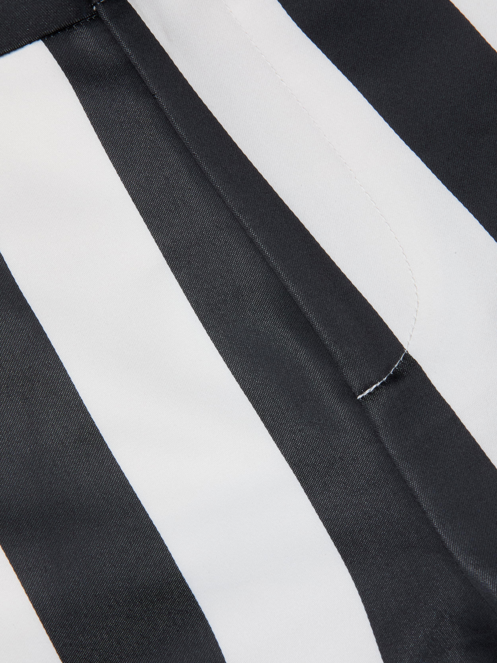 Close-up of black and white striped fabric with a seam and visible stitching, likely part of the Livvy Satin Straight-Leg Trouser.