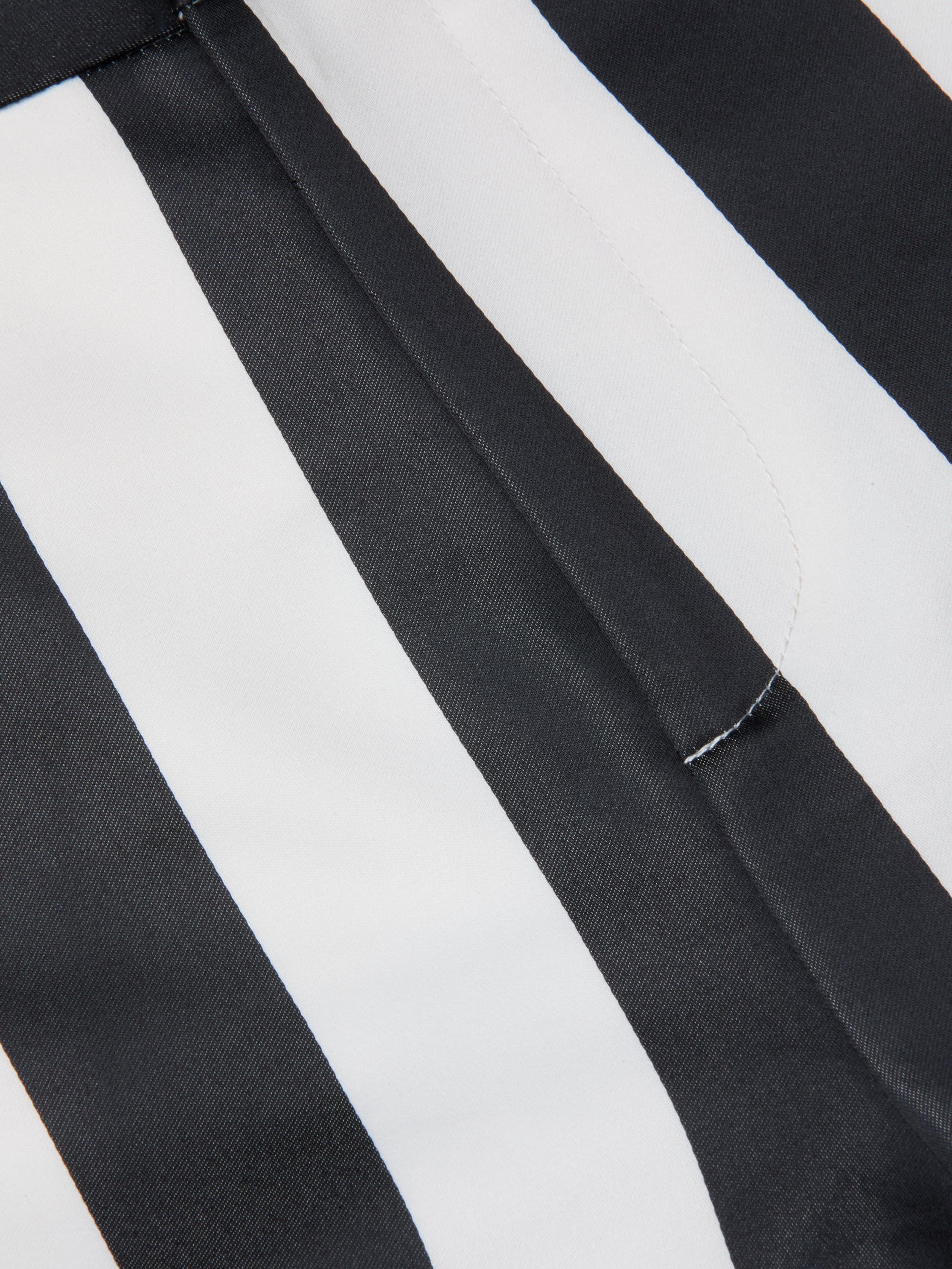 Close-up of black and white striped fabric with a seam and visible stitching, likely part of the Livvy Satin Straight-Leg Trouser.